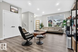 Spacious living area featuring wood-finish flooring, recessed lighting, and a large window with horizontal blinds - 