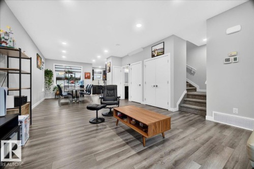 Expansive open-concept living area featuring wood-finish flooring, recessed lighting, and light gray walls - 18139 75 Street, Edmonton, AB 