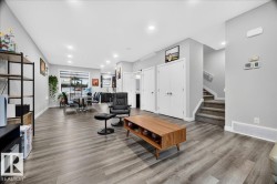 Expansive open-concept living area featuring wood-finish flooring, recessed lighting, and light gray walls - 