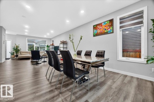 Open-concept living area featuring wood-finish flooring, recessed lighting, and large windows with blinds - 18139 75 Street, Edmonton, AB 