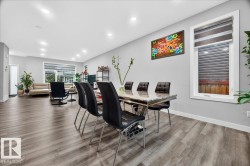 Open-concept living area featuring wood-finish flooring, recessed lighting, and large windows with blinds - 