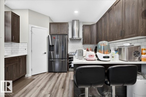 Contemporary kitchen featuring wood-finish flooring, dark wood cabinetry, and white subway tile backsplash - 18139 75 Street, Edmonton, AB 