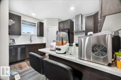 Modern kitchen featuring dark wood-finish cabinetry, white subway tile backsplash, stainless steel appliances, a stainless steel range hood, and light-toned countertops - 