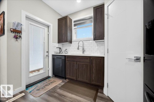 Compact kitchen area featuring dark wood-finish cabinetry, a white subway tile backsplash, and a contemporary gooseneck faucet - 18139 75 Street, Edmonton, AB 