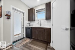 Compact kitchen area featuring dark wood-finish cabinetry, a white subway tile backsplash, and a contemporary gooseneck faucet - 