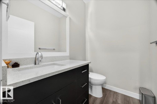 Modern bathroom featuring a dark wood-finish vanity with chrome hardware, an integrated white sink, and a speckled white countertop - 18139 75 Street, Edmonton, AB 