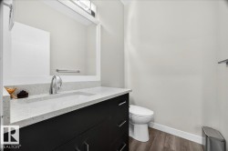 Modern bathroom featuring a dark wood-finish vanity with chrome hardware, an integrated white sink, and a speckled white countertop - 