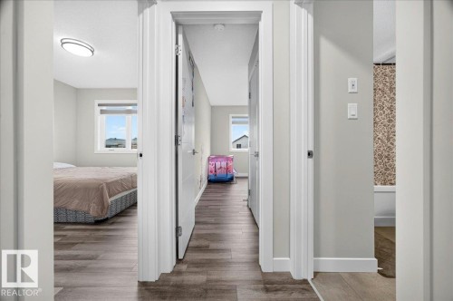 Hallway offering access to multiple rooms, featuring wood-finish flooring, light grey wall paint, and white trim - 18139 75 Street, Edmonton, AB 