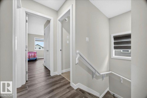 Hallway featuring wood-finish flooring, light grey walls, white trim, and white doors - 18139 75 Street, Edmonton, AB 