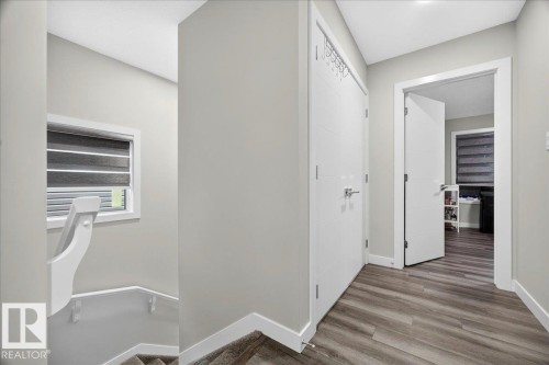 Upper-level landing featuring wood-finish flooring, light gray wall paint, white trim, and a window with horizontal blinds - 18139 75 Street, Edmonton, AB 