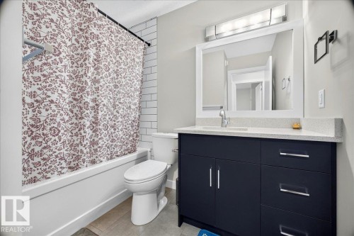 Bathroom featuring subway tile shower surround, a white tub, and a white toilet - 18139 75 Street, Edmonton, AB 
