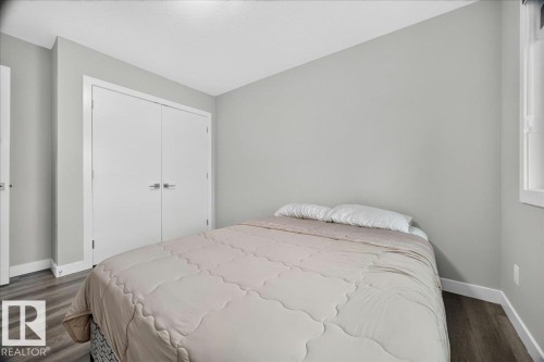 Bedroom featuring light gray walls, wood-finish flooring, white baseboards, and a white closet with double doors - 18139 75 Street, Edmonton, AB 