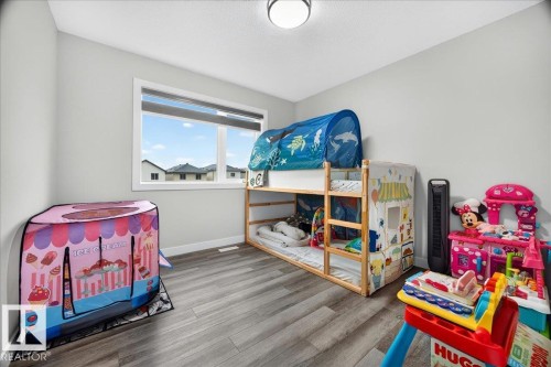 Light-filled room featuring wood-finish flooring, white baseboards, and a double window with exterior views - 18139 75 Street, Edmonton, AB 