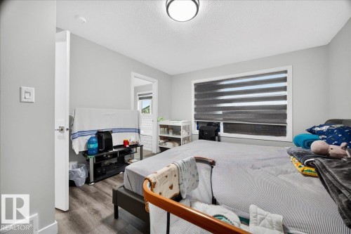 Bedroom featuring modern wood-finish flooring, light gray wall paint, and a contemporary ceiling light fixture - 18139 75 Street, Edmonton, AB 