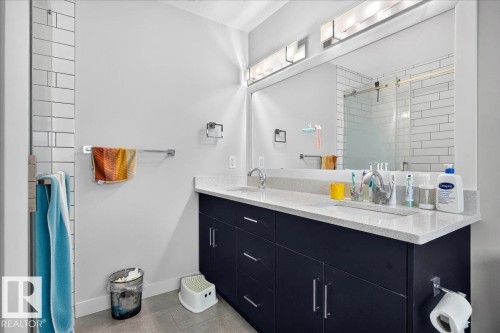 Contemporary bathroom featuring a double vanity with dark cabinetry, integrated sinks, and light-toned countertops - 18139 75 Street, Edmonton, AB 