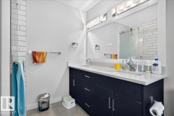 Contemporary bathroom featuring a double vanity with dark cabinetry, integrated sinks, and light-toned countertops - 