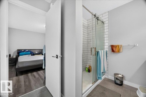 Glass-enclosed shower with white subway tile surround, matte gray wall paint, and wood-finish flooring extending into the adjoining room - 18139 75 Street, Edmonton, AB 