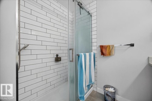 Shower enclosure featuring white subway tile, a sliding glass door, and a built-in shower niche - 18139 75 Street, Edmonton, AB 