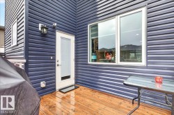 Exterior featuring dark blue horizontal siding, a light wood-finish deck, and a white framed door - 
