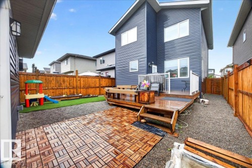 Spacious backyard featuring a multi-level wood deck, wood-finish patio tiles, gravel landscaping, a section of artificial turf, and a full perimeter wood fence - 18139 75 Street, Edmonton, AB 