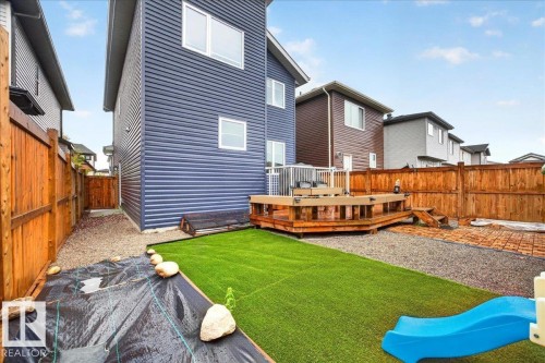 Backyard featuring a multi-level wood deck, artificial turf, gravel pathways, and a wood privacy fence - 18139 75 Street, Edmonton, AB 