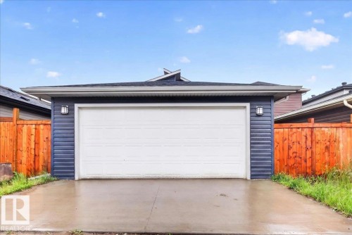 Detached garage featuring a white overhead door, dark blue horizontal siding, and two exterior wall-mounted light fixtures - 18139 75 Street, Edmonton, AB 