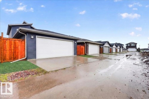 Attached garage with a white overhead door, dark blue siding, and a concrete driveway - 18139 75 Street, Edmonton, AB 
