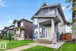Modern two-story residence with a blue-gray siding exterior, a contrasting white front door, and a covered porch - 