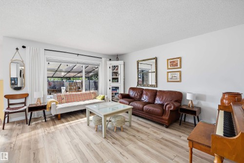 Spacious living area featuring wood-finish flooring, light-toned walls, and a large sliding glass door - 25 Halladay Boulevard, Spruce Grove, AB - Indoor Photo Showing Living Room