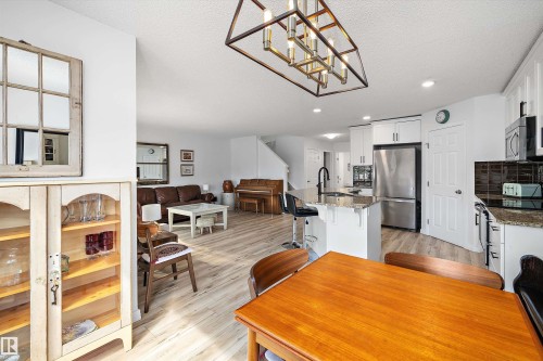 Open-concept living area featuring a kitchen with white cabinetry, granite countertops, and stainless steel appliances - 25 Halladay Boulevard, Spruce Grove, AB - Indoor