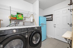 Laundry area featuring gray tile flooring, a white paneled door, and a built-in wire shelving system - 