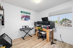 Bright room featuring light wood-finish flooring and a large window with privacy blinds - 