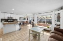 Open-concept living space featuring wood-finish flooring, a white kitchen island with bar seating, and white cabinetry - 25 Halladay Boulevard, Spruce Grove, AB  - Indoor 
