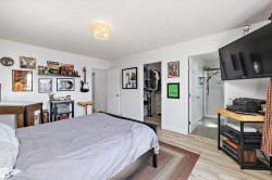 Bedroom featuring wood-finish flooring, white walls, and a contemporary ceiling light fixture - 