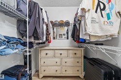 Walk-in closet featuring built-in wire shelving, hanging rods, light wood-finish flooring, and a mirrored wall accent - 