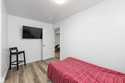 Room featuring neutral white walls, wood-finish flooring, and a white six-panel door - 