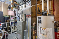 Utility area featuring a water heater and furnace with exposed ductwork and PVC piping - 
