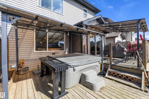 Expansive wooden deck featuring a hot tub, a built-in outdoor bar, and a covered patio area with string lights - 25 Halladay Boulevard, Spruce Grove, AB - Outdoor With Exterior