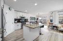 Kitchen featuring white cabinetry, stainless steel appliances, a center island with a stone countertop and seating, and wood-finish flooring - 25 Halladay Boulevard, Spruce Grove, AB  - Indoor Photo Showing Kitchen With Double Sink 