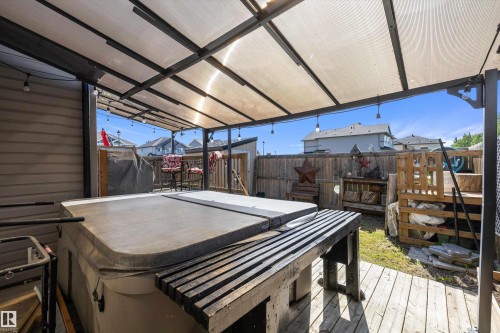 Covered outdoor living area featuring a hot tub with an integrated wooden surround - 25 Halladay Boulevard, Spruce Grove, AB - Outdoor With Deck Patio Veranda With Exterior