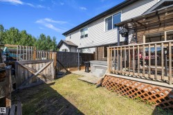 Rear exterior featuring a wooden deck with lattice skirting, an integrated spa, and a privacy fence - 
