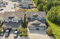 Exterior featuring multi-dormer rooflines, light gray siding, white trim accents, and attached garages - 