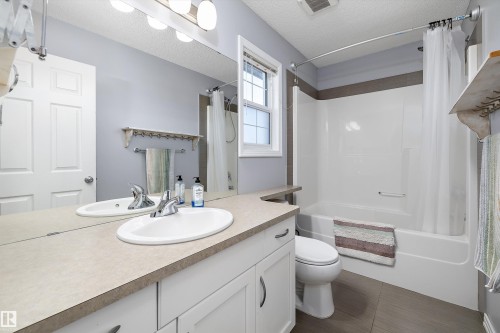 Main Bathroom featuring a white vanity with an integrated sink, a large wall-mounted mirror, a tub-shower combination with white surround, and a window with white trim - 25 Halladay Boulevard, Spruce Grove, AB - Indoor Photo Showing Bathroom