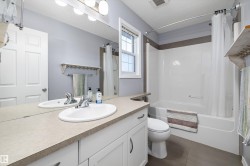 Main Bathroom featuring a white vanity with an integrated sink, a large wall-mounted mirror, a tub-shower combination with white surround, and a window with white trim - 