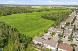Residential neighborhood bordered by expansive green fields and mature tree lines - 