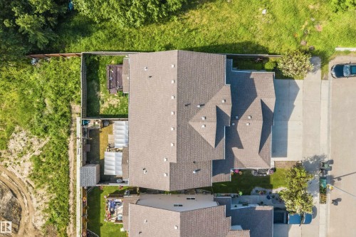 Aerial perspective showcasing the property's pitched roofline, paved driveway, and established fencing - 25 Halladay Boulevard, Spruce Grove, AB - Outdoor