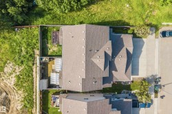 Aerial perspective showcasing the property's pitched roofline, paved driveway, and established fencing - 