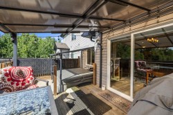 Expansive outdoor deck featuring a covered pergola, wooden decking, and sliding glass door access - 