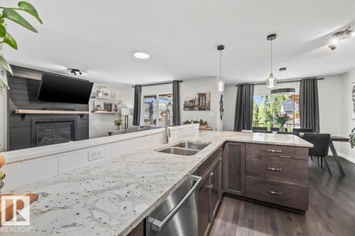 Spacious kitchen featuring an undermount double-basin sink, stainless steel dishwasher, and stone countertops - 14 Edinburgh Crt N, St. Albert, AB 