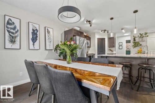 Open-concept dining area featuring dark wood-finish flooring, a modern circular chandelier, and light gray walls - 14 Edinburgh Crt N, St. Albert, AB 